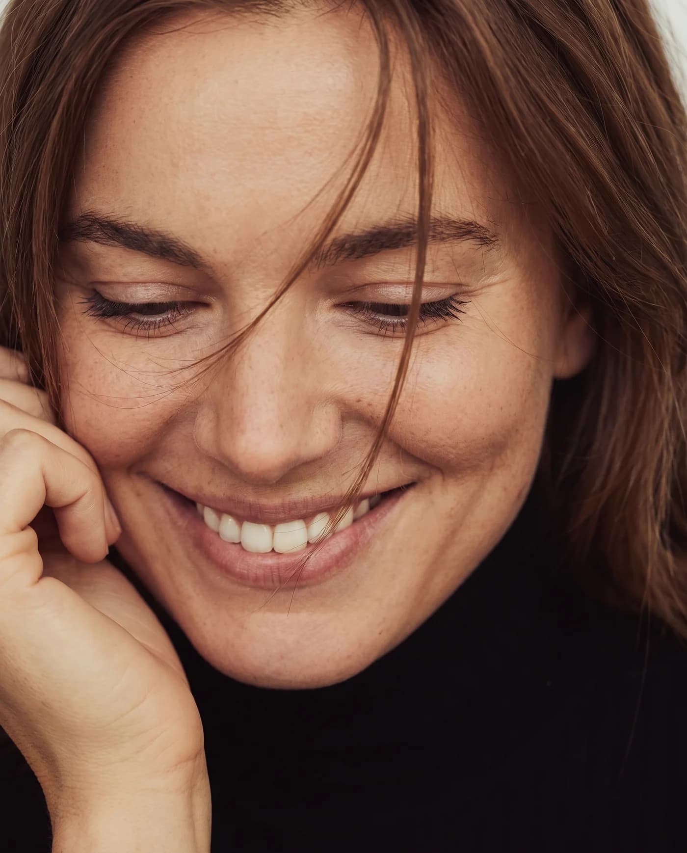 A candid close-up of a woman smiling in soft natural light